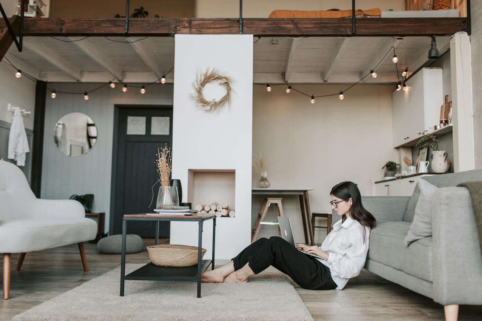 Cozy loft apartment with a woman working on a laptop, showcasing modern remote work lifestyle.