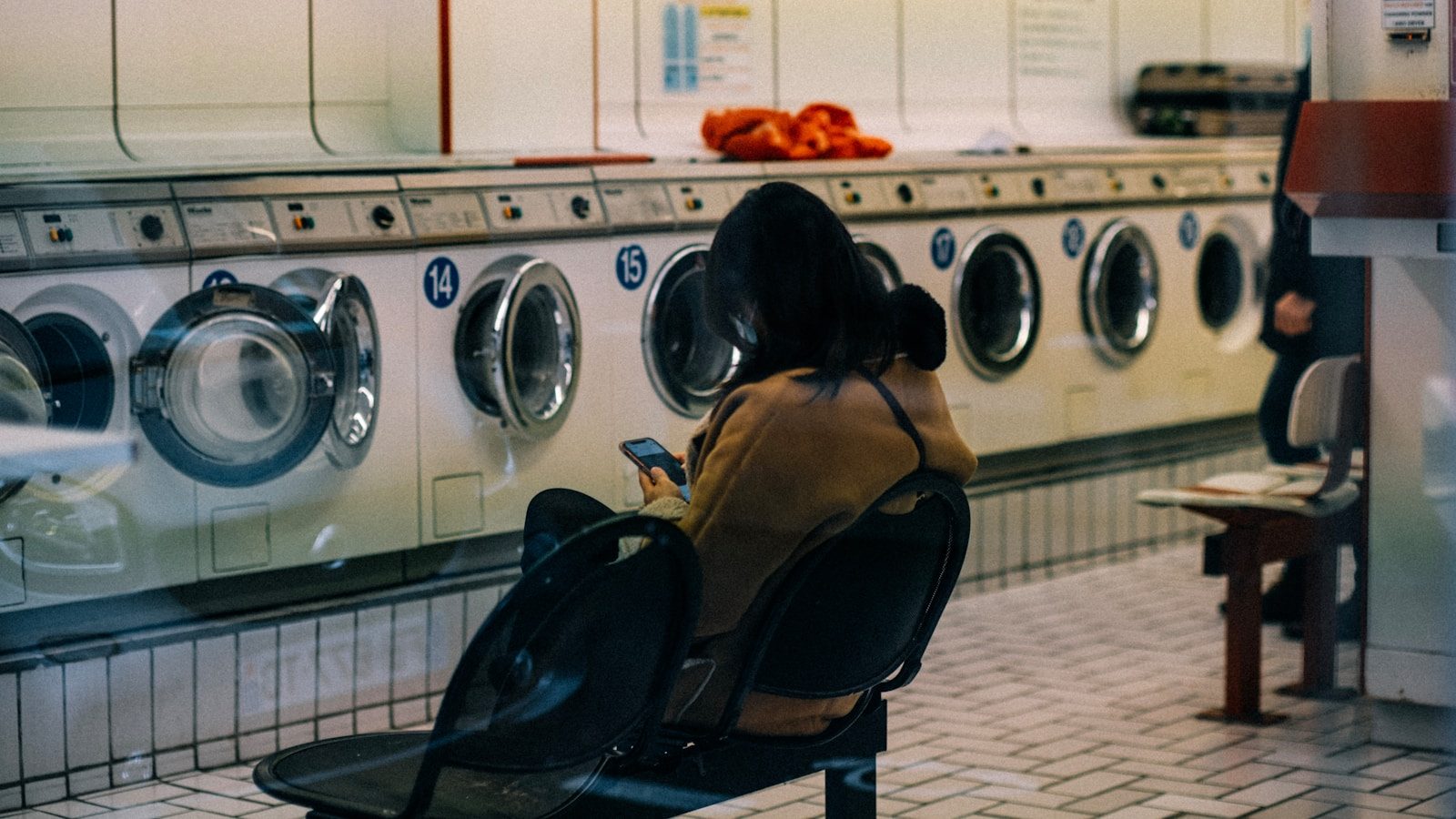 a woman sitting on a chair in front of a row of washers