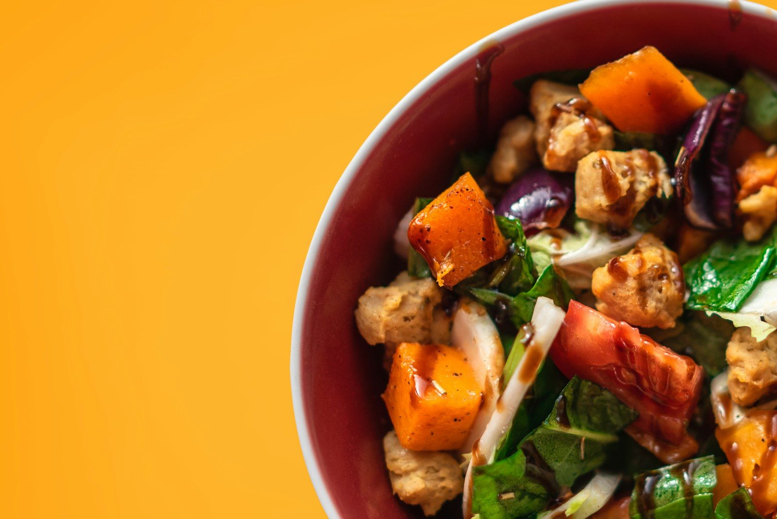 a red bowl filled with meat and vegetables