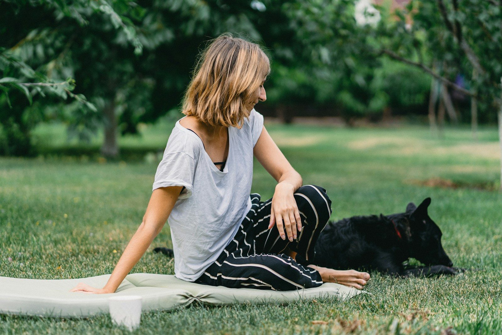 woman sitting on ground beside black dog