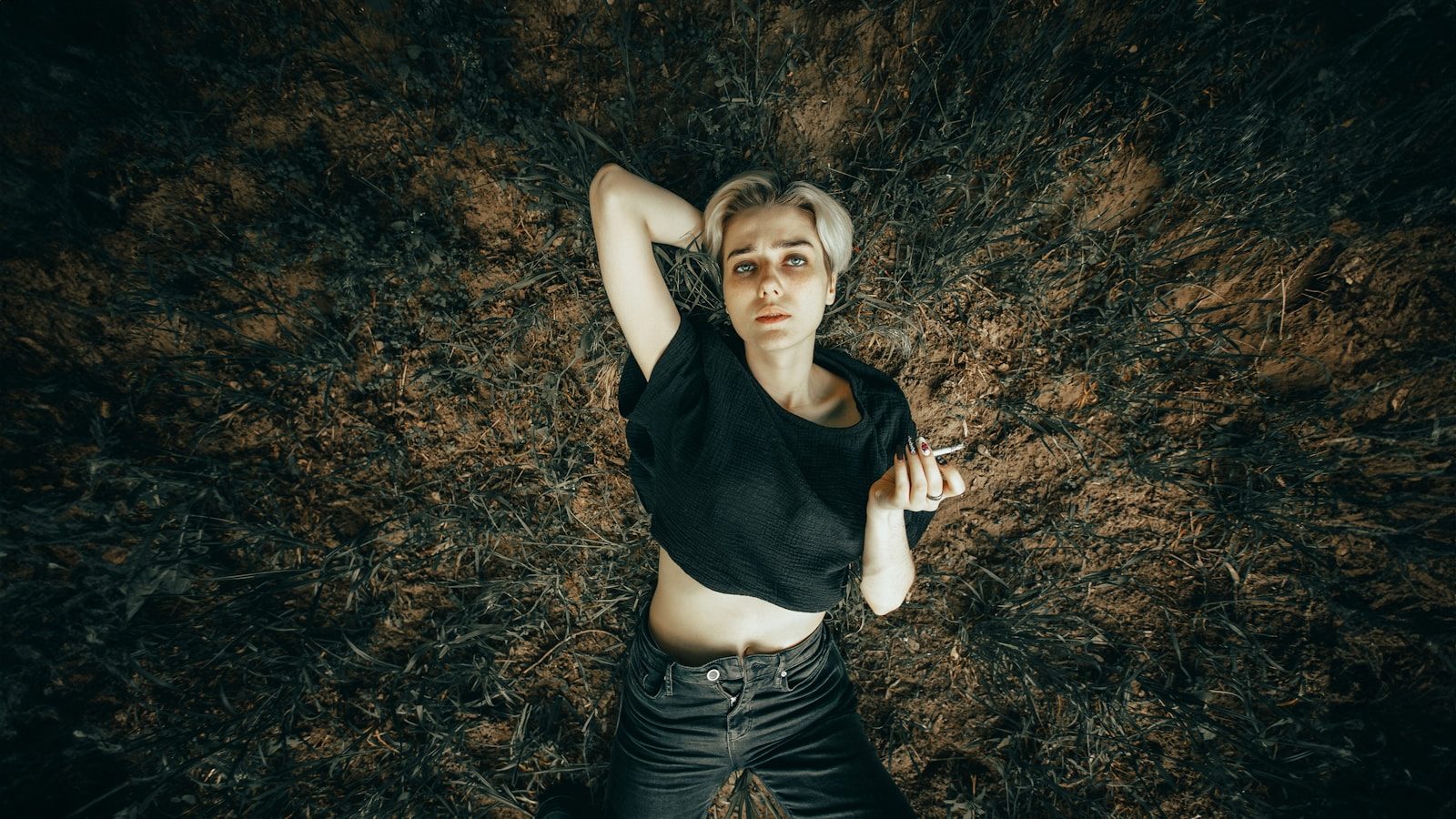 Young woman lying on the grass with eyes wide.