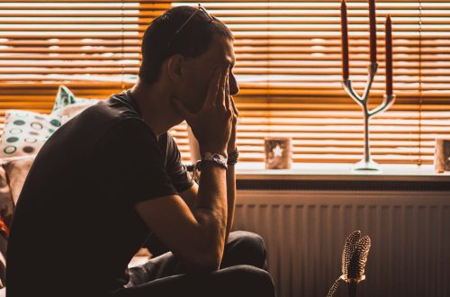 man sitting on chair covering his eyes