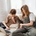 Two children enjoying leisure time on a sofa, using a laptop together indoors.