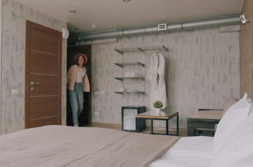 A woman in a hat and jacket entering a modern hotel room