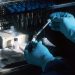 gloved hands drawing vaccine from vial with syringe